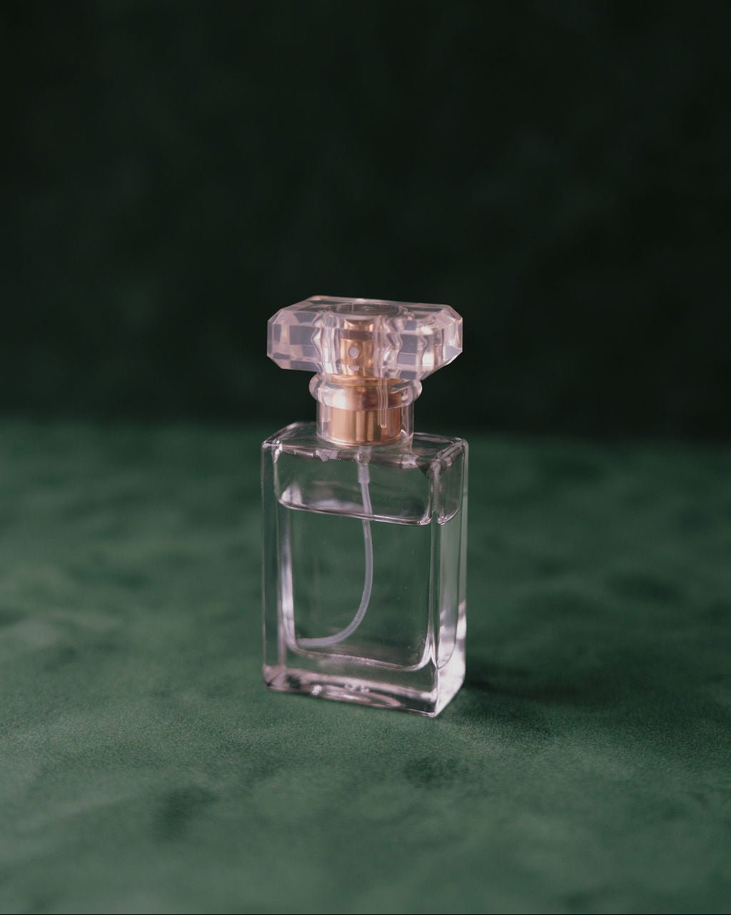 Green Clear perfume bottle with gold cap on a green suede matboard textured surface